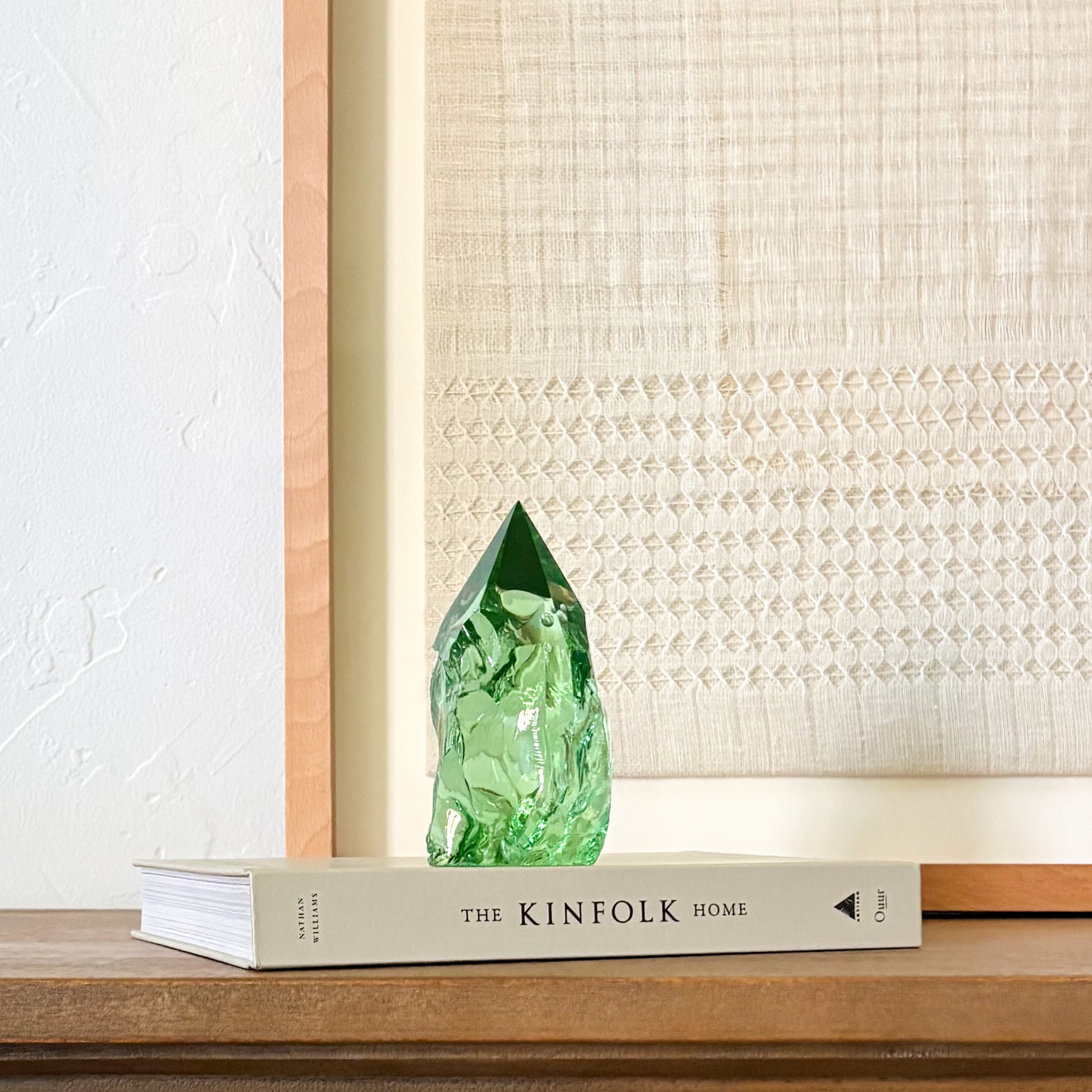 Green glass crystal point centerpiece with organic texture, styled on book in neutral home setting