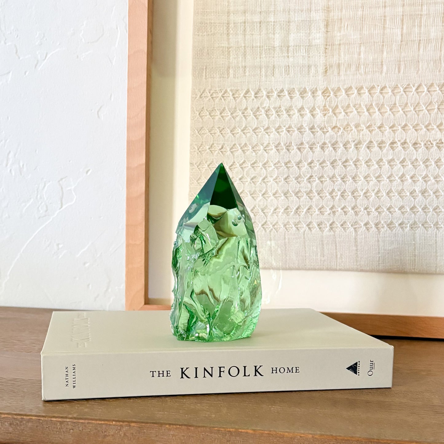 Translucent green glass point sculpture on stacked book, minimalist rustic home decor