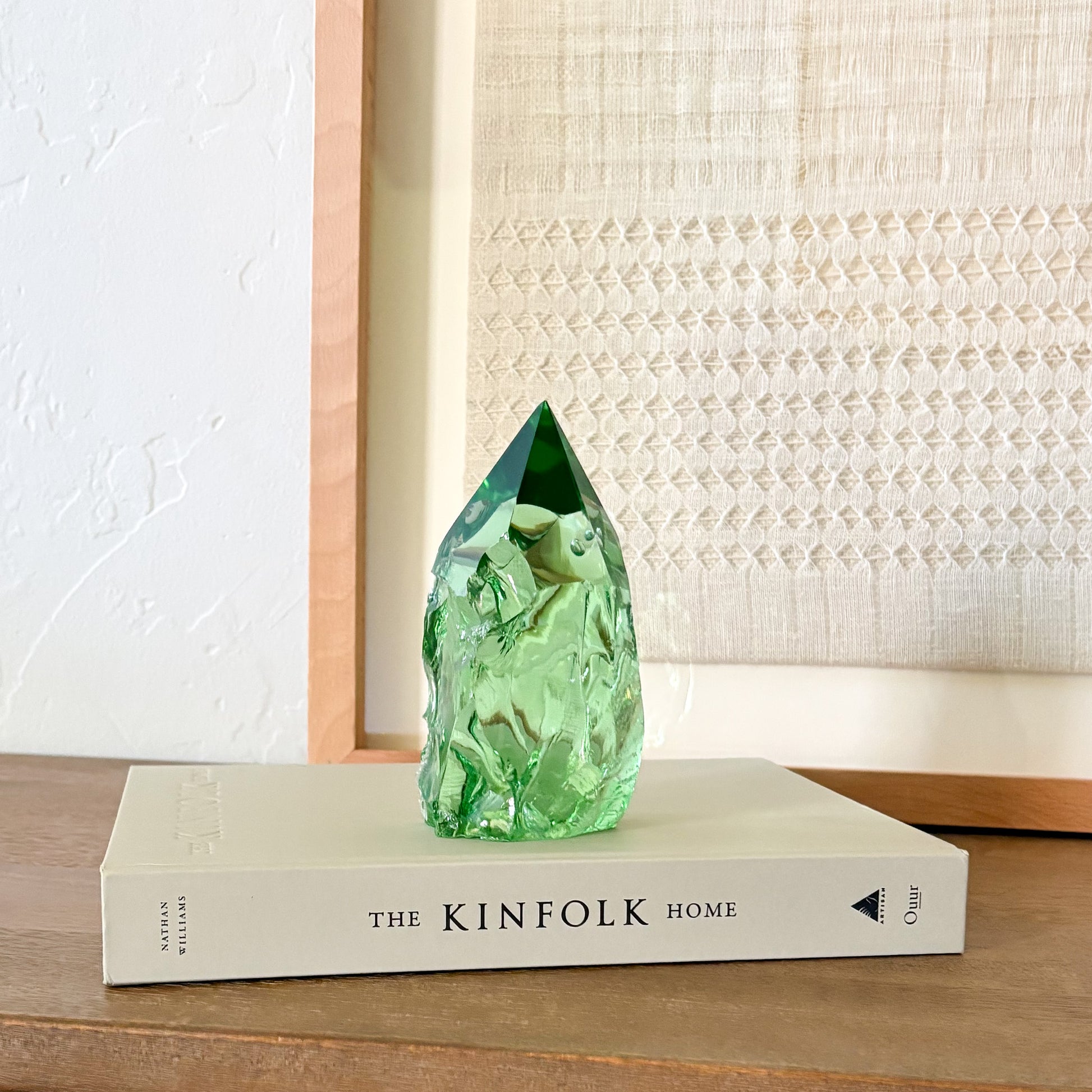 Translucent green glass point sculpture on stacked book, minimalist rustic home decor