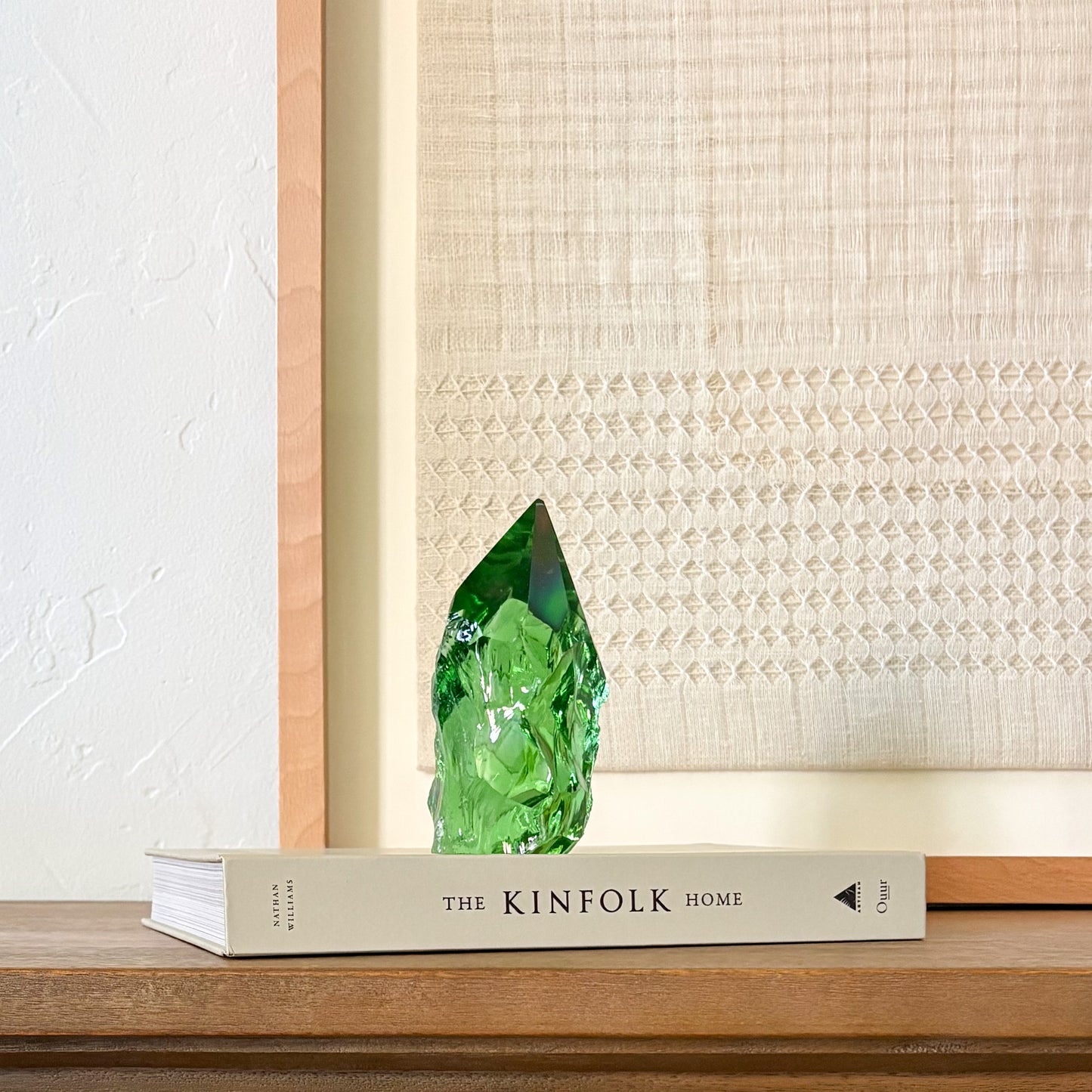 Artisan green glass crystal point with textured finish, styled in minimalist home decor scene