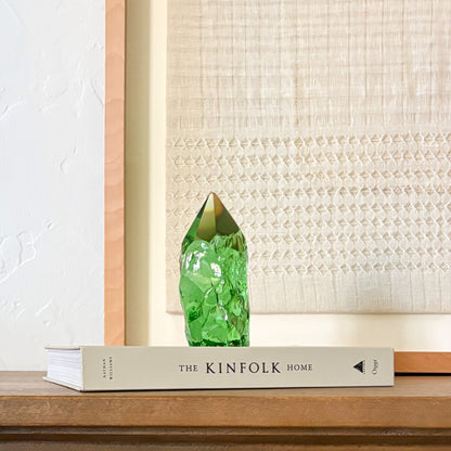 Green glass crystal point centerpiece with organic texture, styled on book in neutral home setting