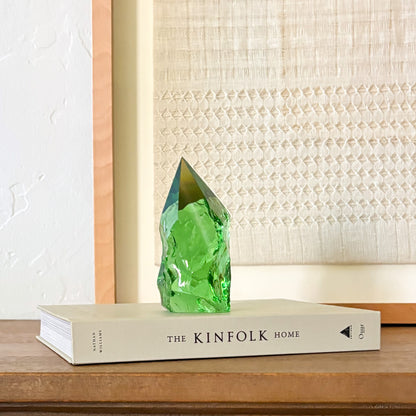 Translucent green glass point sculpture on stacked book, minimalist rustic home decor