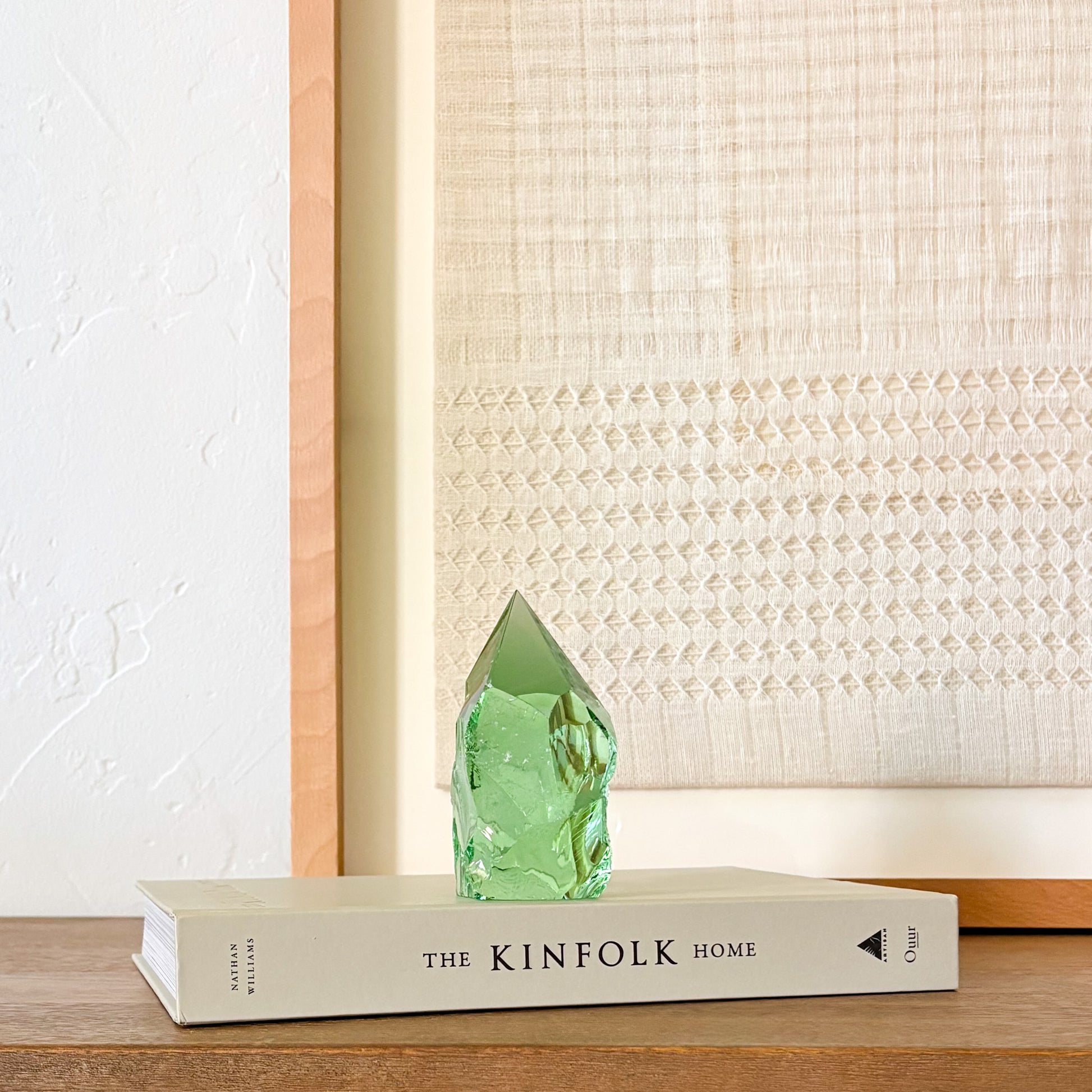 Green glass crystal point centerpiece with organic texture, styled on book in neutral home setting