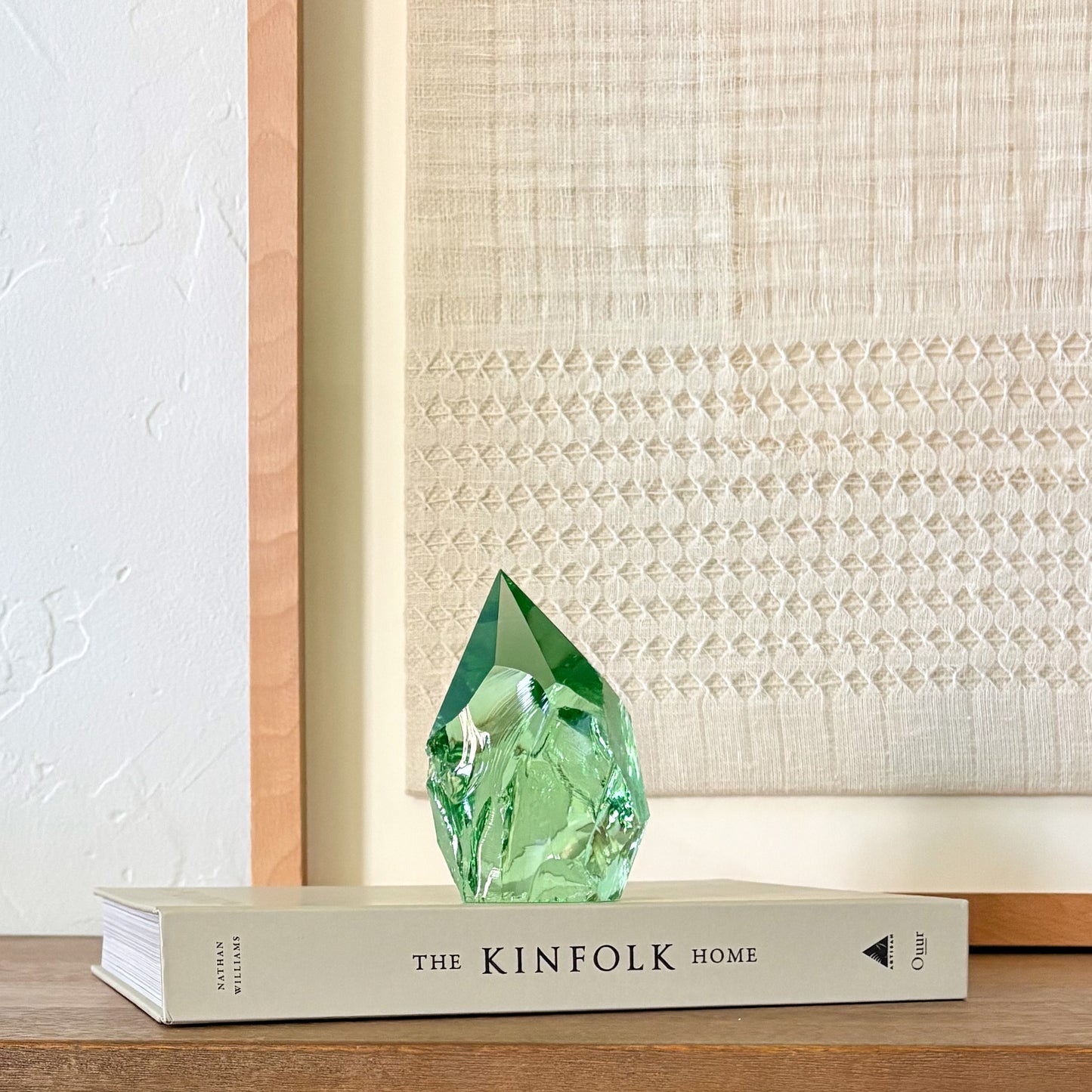 Translucent green glass point sculpture on stacked book, minimalist rustic home decor