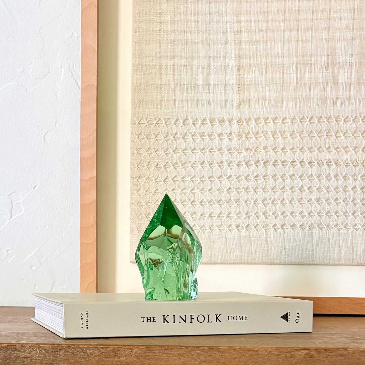 Artisan green glass crystal point with textured finish, styled in minimalist home decor scene