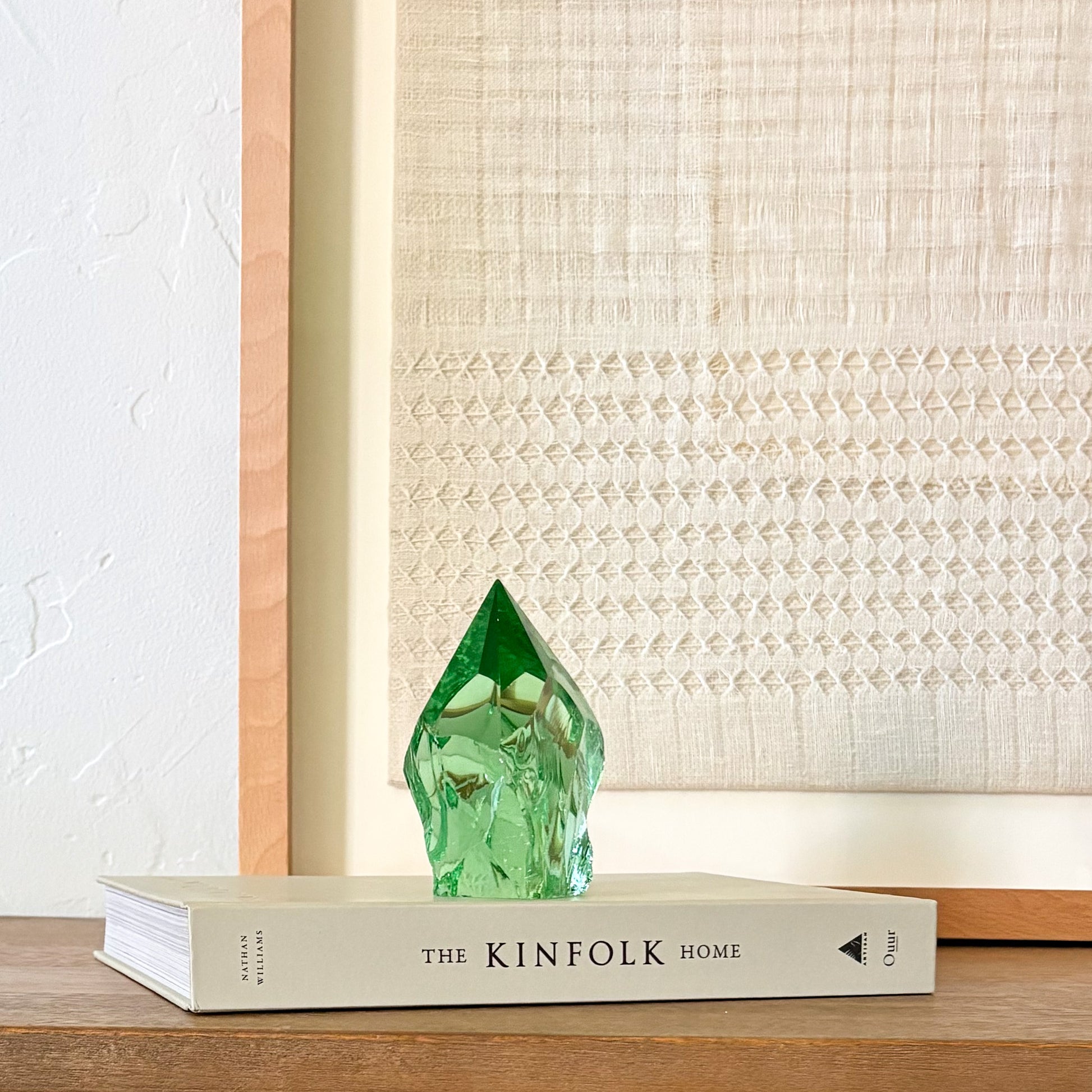 Artisan green glass crystal point with textured finish, styled in minimalist home decor scene