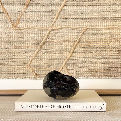 Decorative black crystal stone on a book titled 'Memories of Home' with a textured wall background