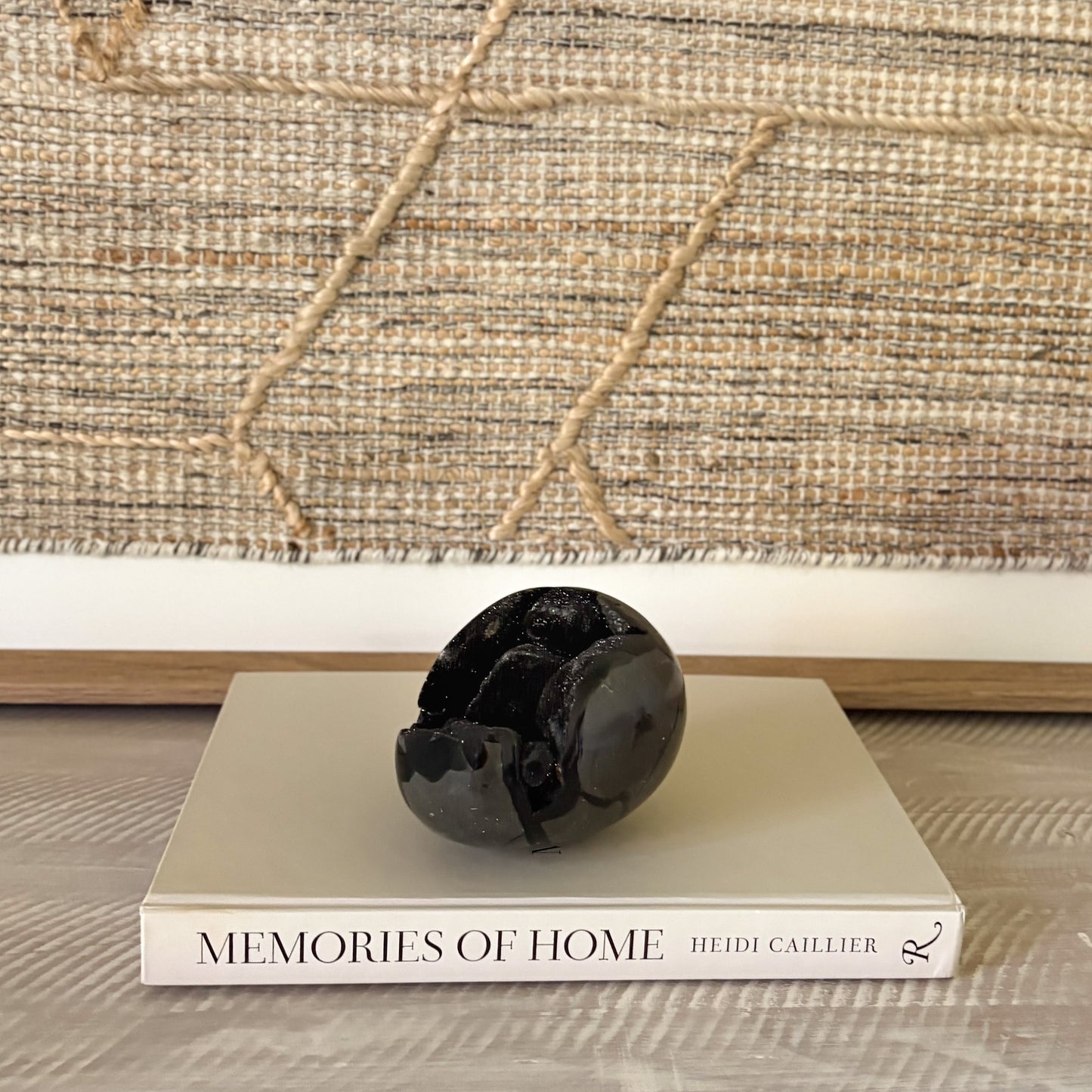 Decorative black crystal egg on a book titled 'Memories of Home' with a textured wall in the background