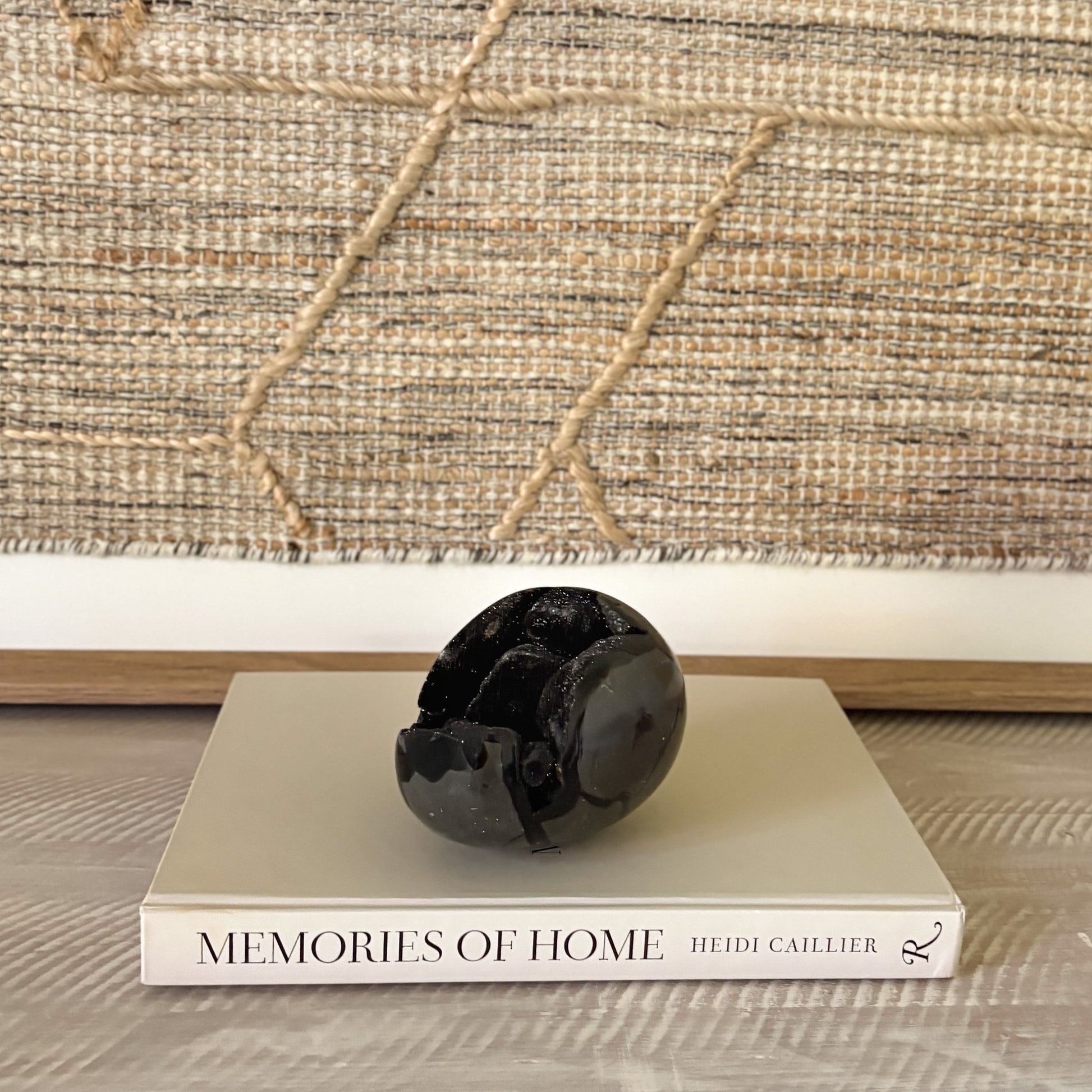 Decorative black crystal egg on a book titled 'Memories of Home' with a textured wall in the background