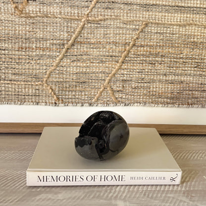 Decorative black crystal egg on a book titled 'Memories of Home' with a textured wall in the background