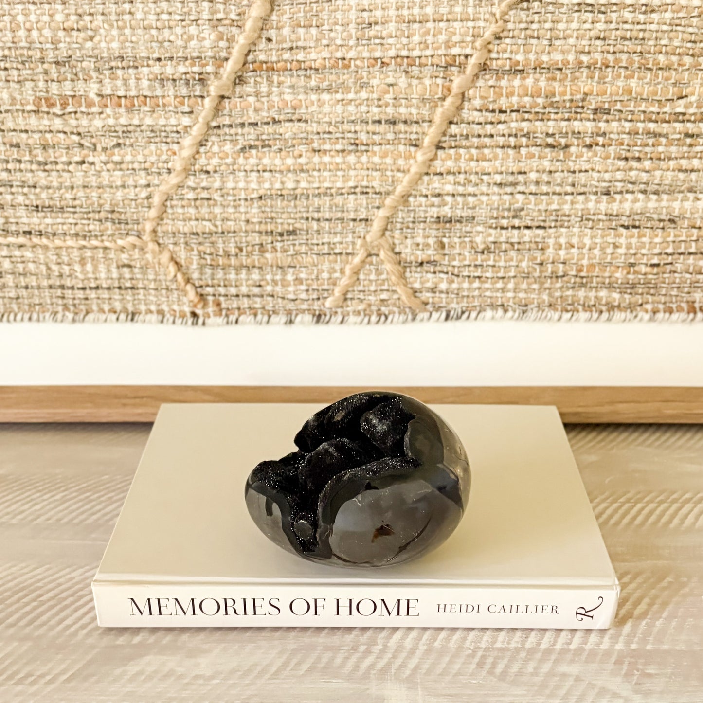 Decorative black crystal stone on a book titled 'Memories of Home' with a woven background