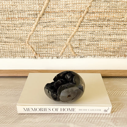 Decorative black crystal stone on a book titled 'Memories of Home' with a woven background