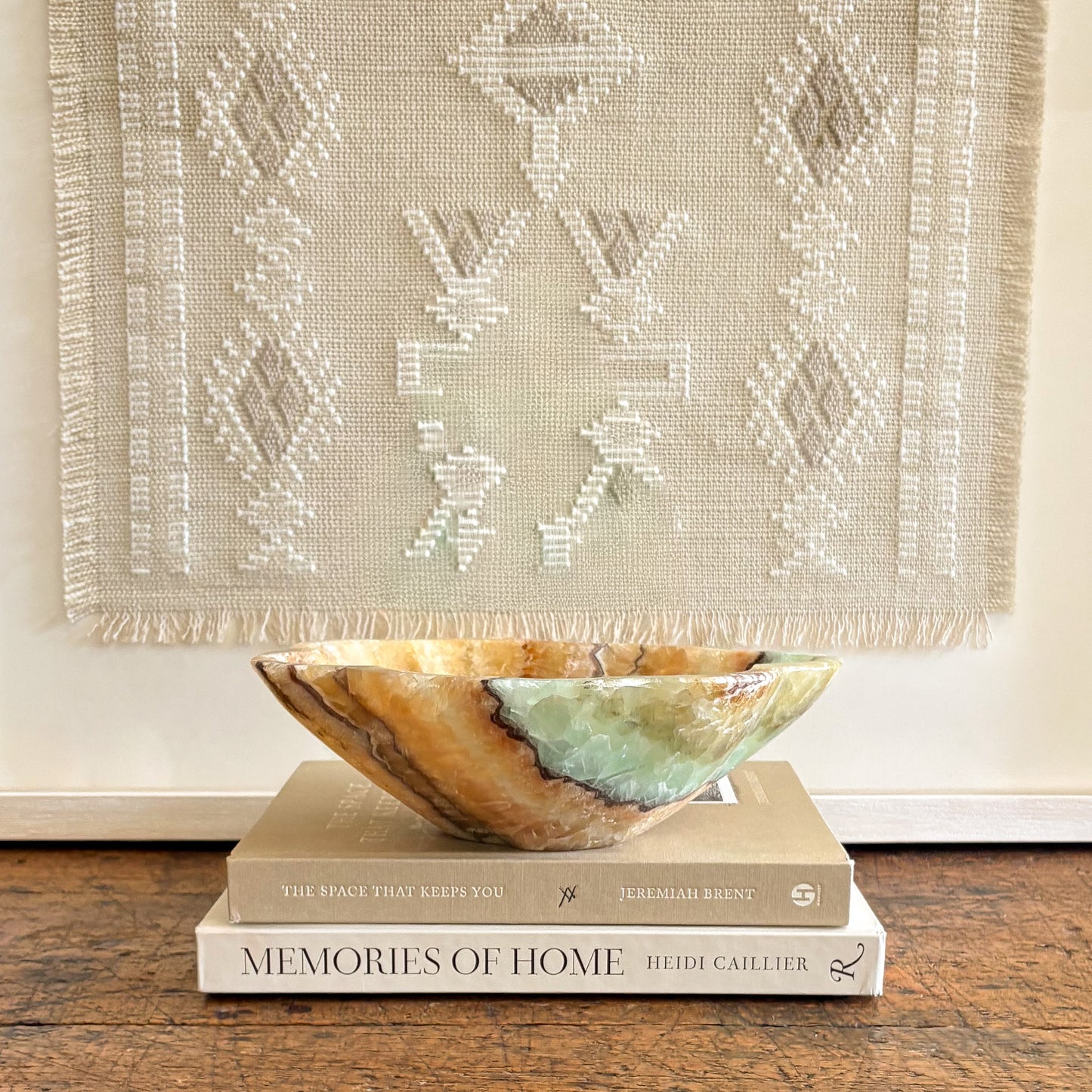 Serpentine onyx decorative bowl with green and honey veining styled on stacked books as modern home decor