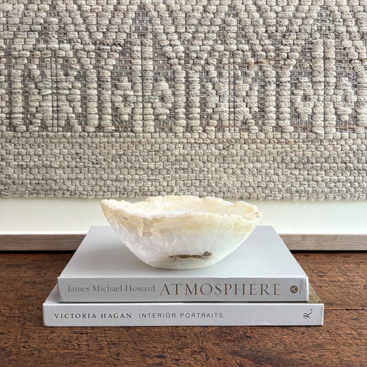 Decorative bowl on books with a textured wall in the background