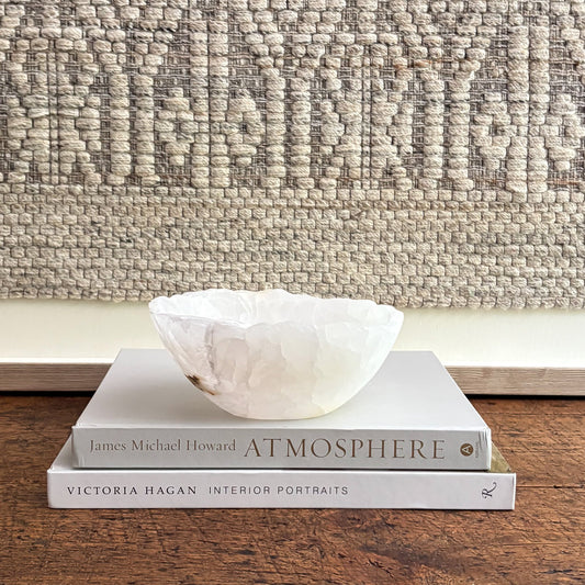 White stone bowl on a stack of books with a textured wall in the background