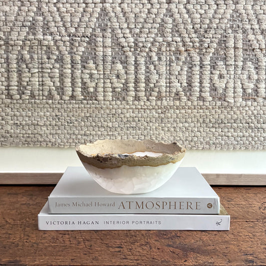 Decorative onyx bowl on top of two books with a textured wall in the background