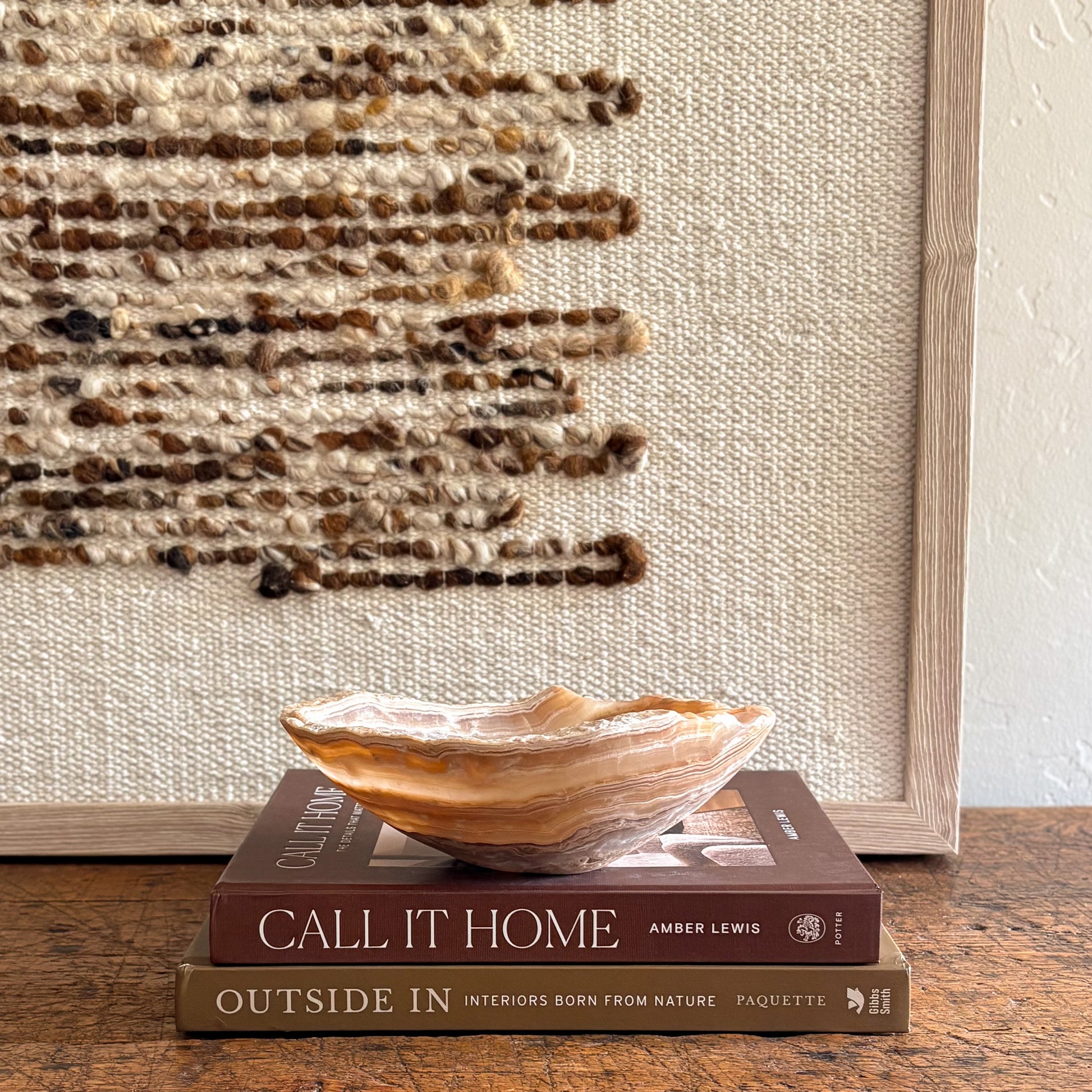Hand-carved amber onyx bowl displayed on stacked books in a neutral home setting