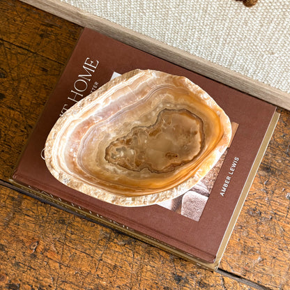 Polished amber onyx bowl styled as home décor on stacked design books