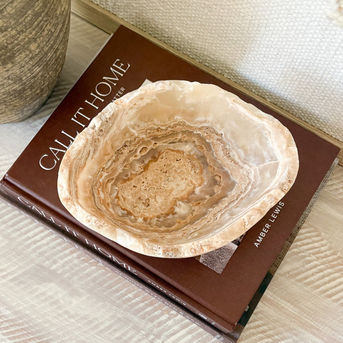 Decorative small hand-carved amber onyx bowl styled in a neutral modern interior.