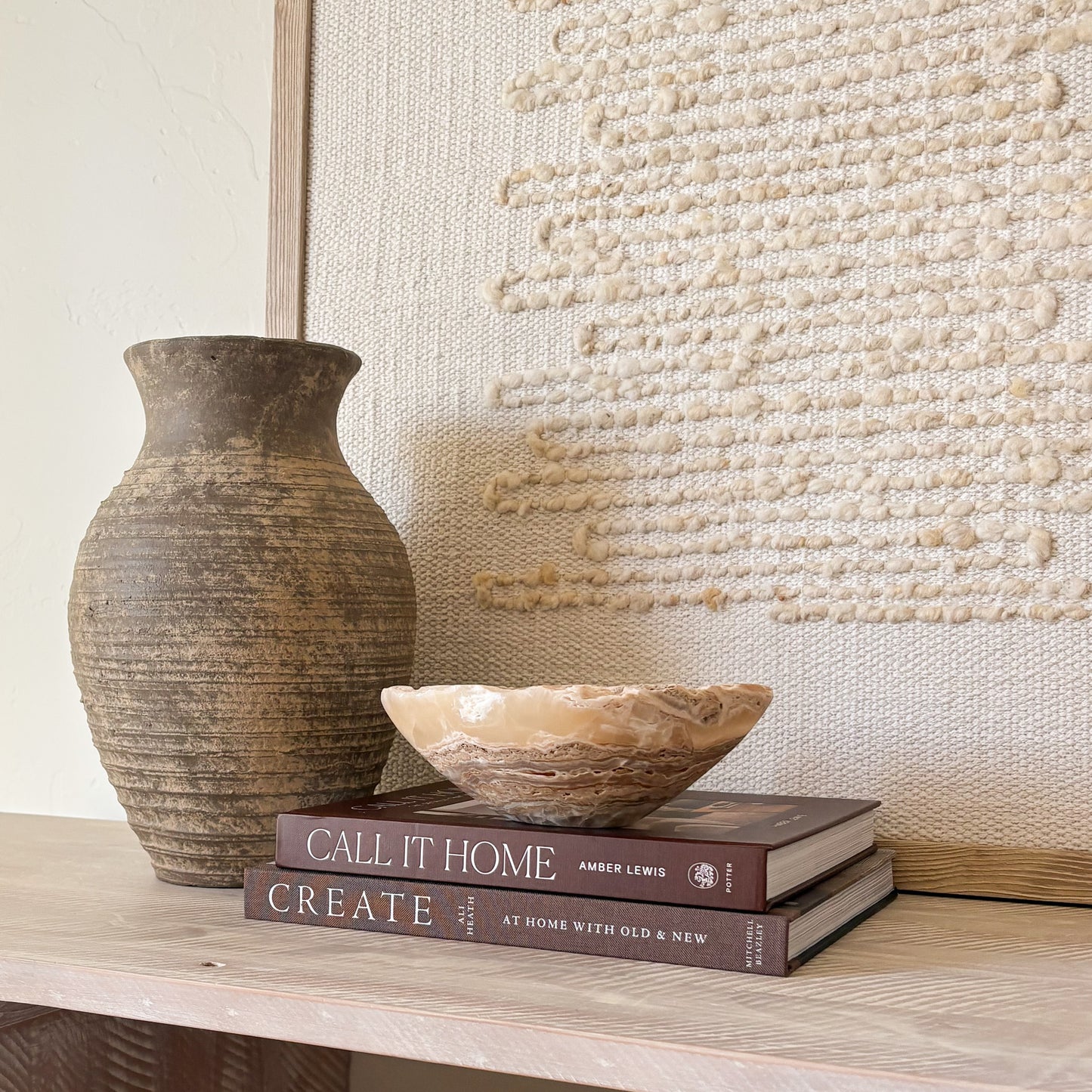 Small hand-carved amber onyx bowl with natural veining, styled on books for modern home décor