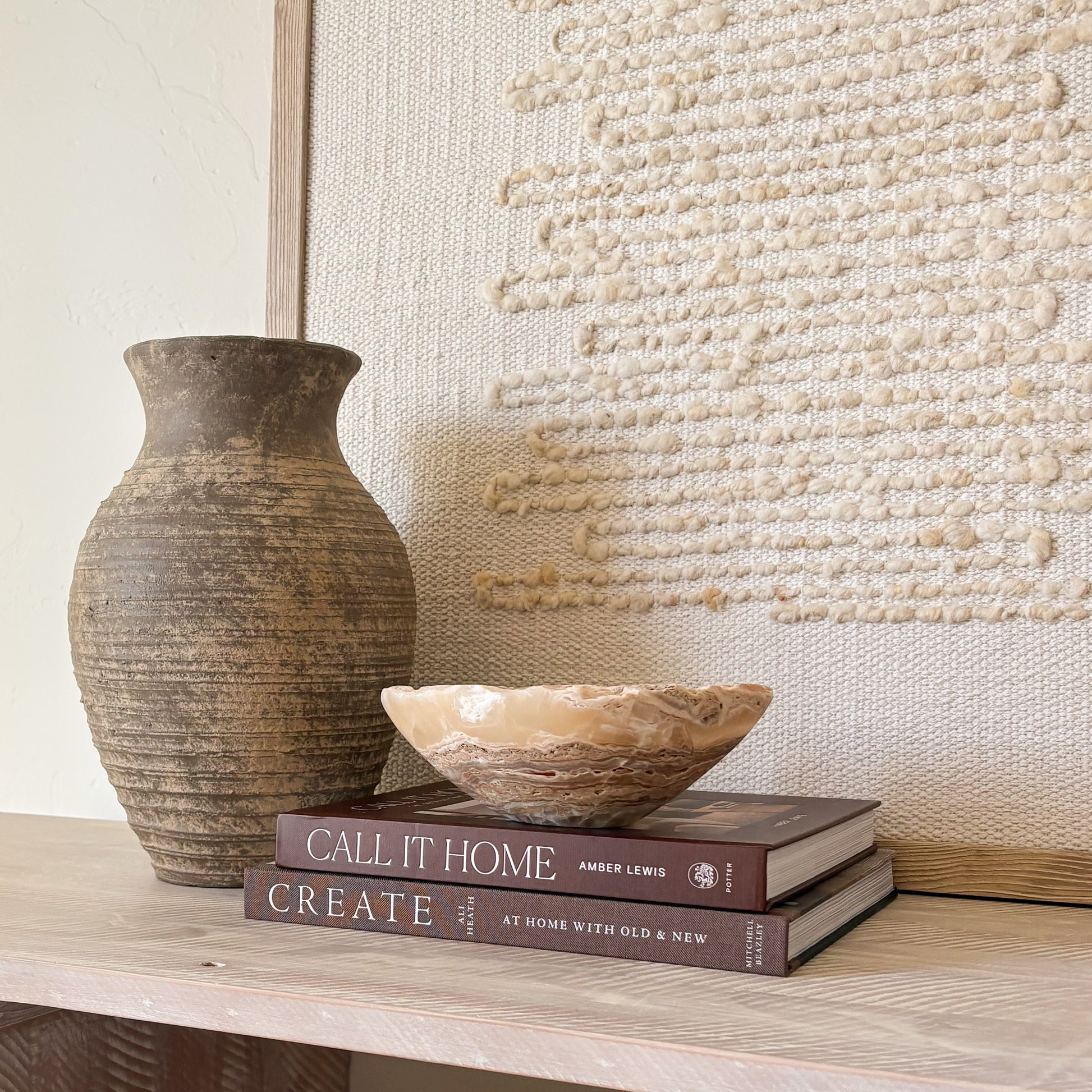 Small hand-carved amber onyx bowl with natural veining, styled on books for modern home décor