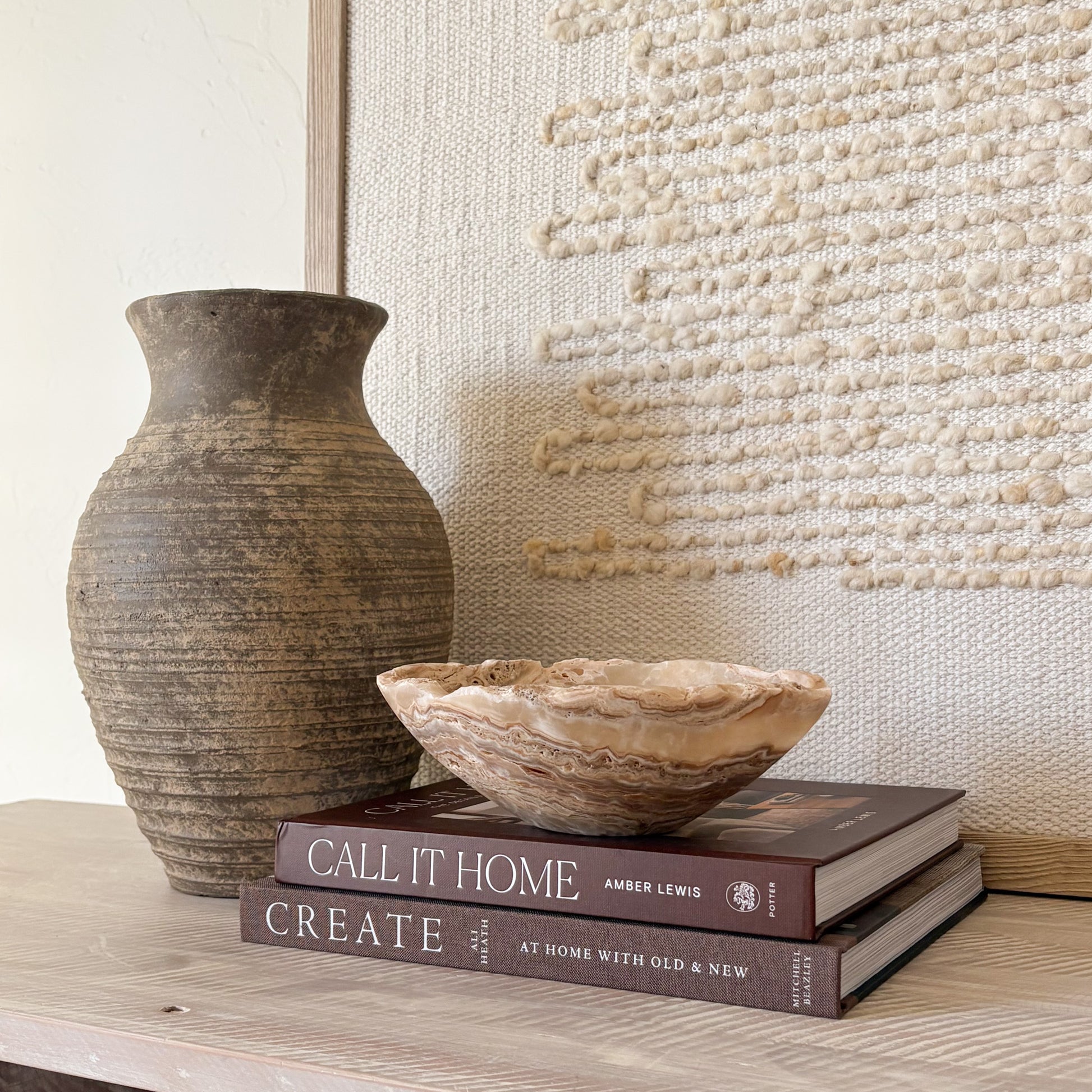 Small hand-carved amber onyx bowl with natural veining, styled on stacked books