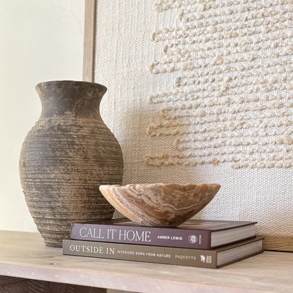 Small hand-carved amber onyx bowl resting on stacked books
