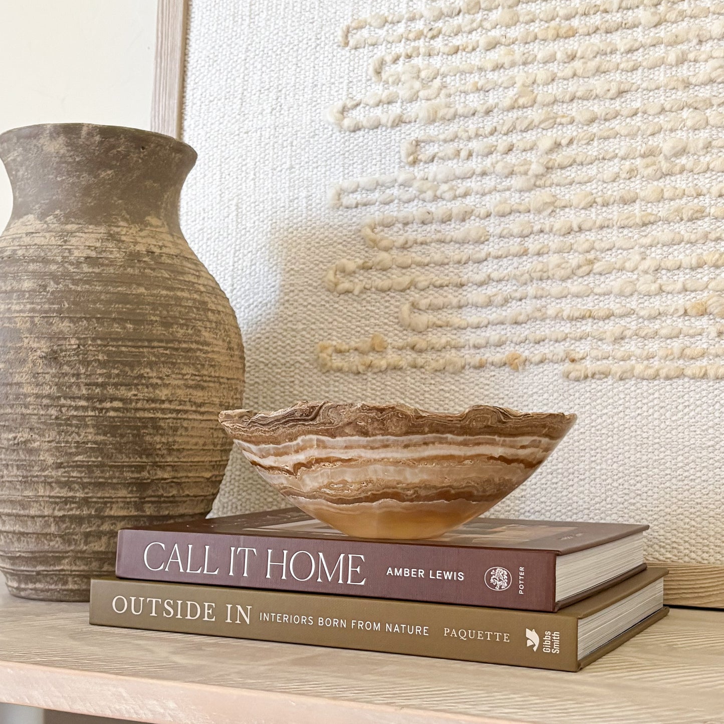 Small hand carved amber onyx bowl with soft natural veining displayed on stacked design books