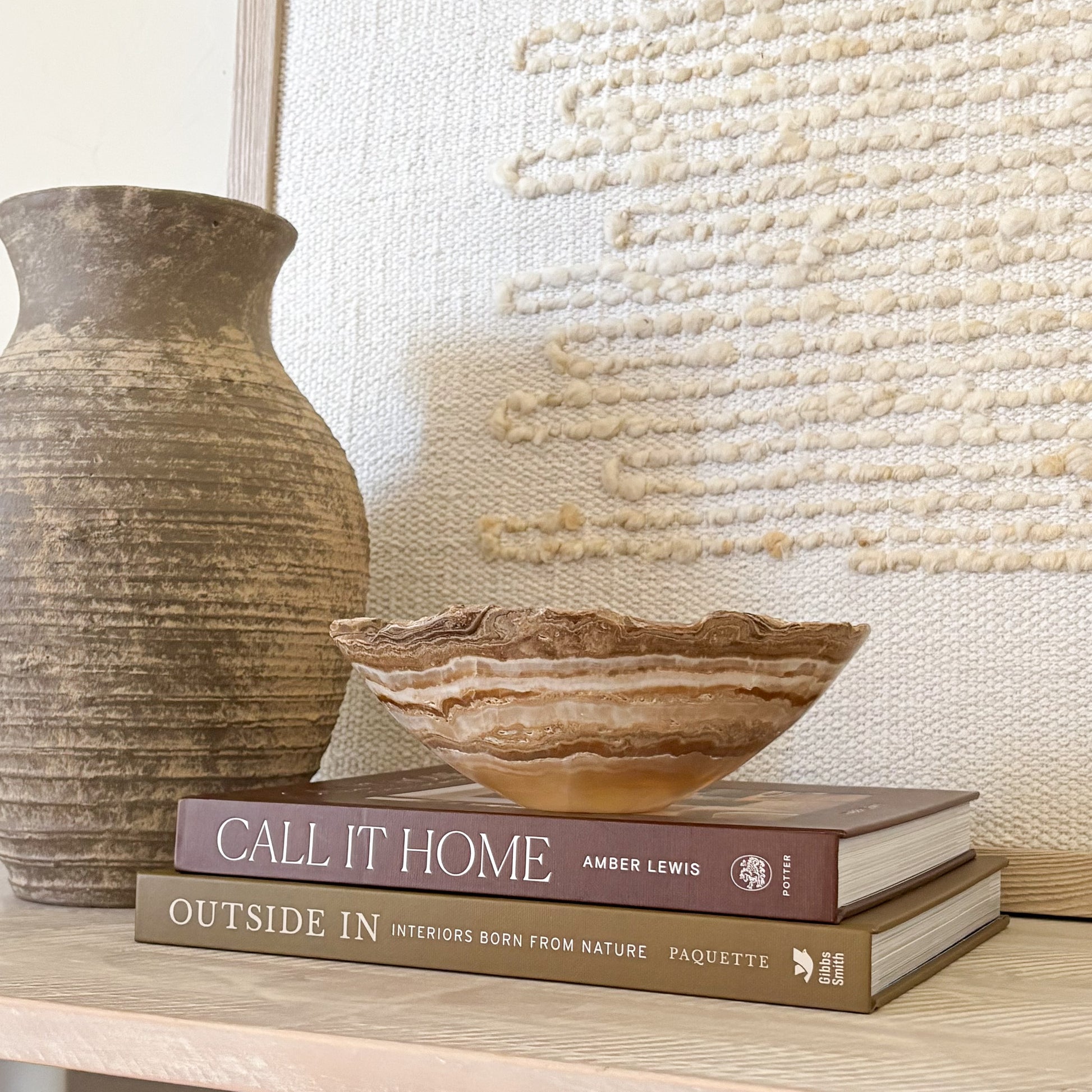 Small hand carved amber onyx bowl with soft natural veining displayed on stacked design books