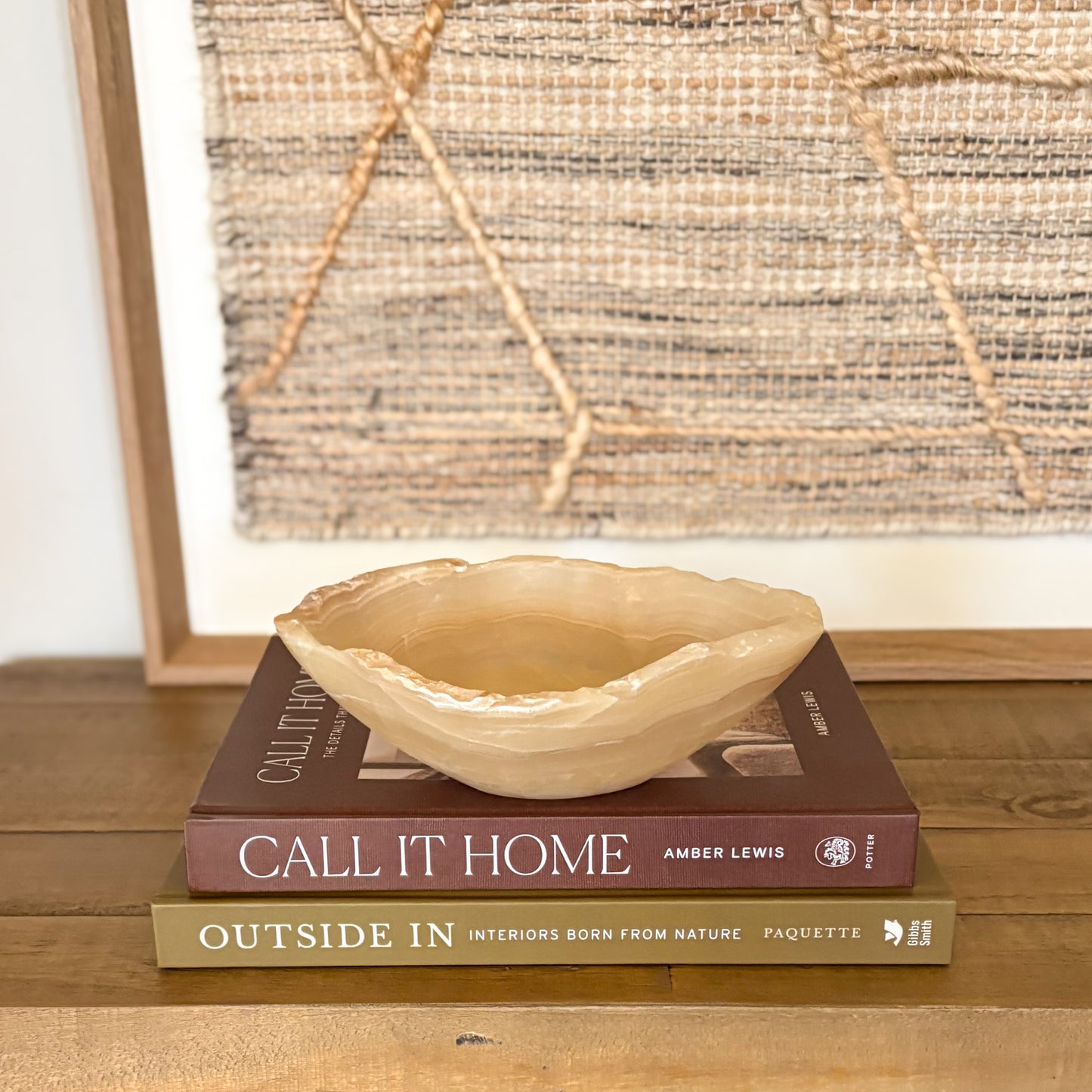 Small hand carved amber onyx bowl with soft natural veining displayed on stacked design books
