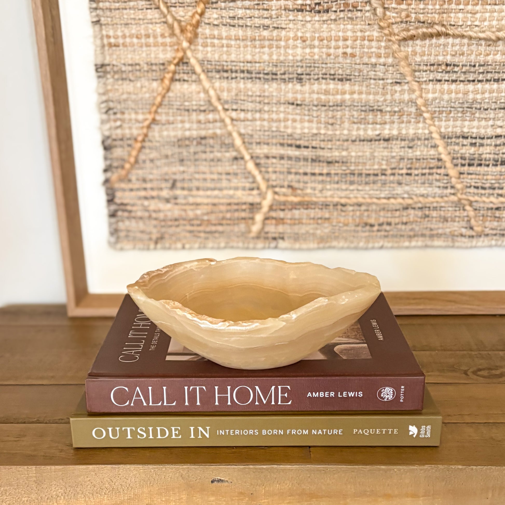 Small hand carved amber onyx bowl with soft natural veining displayed on stacked design books
