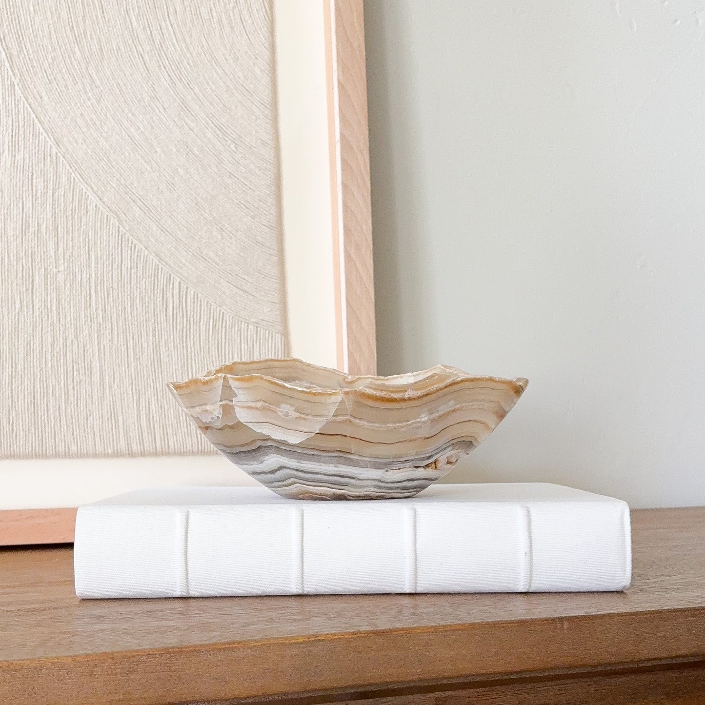 Small amber onyx stone bowl with smooth polished interior and layered cream, honey, and gray veining, handcrafted decorative bowl