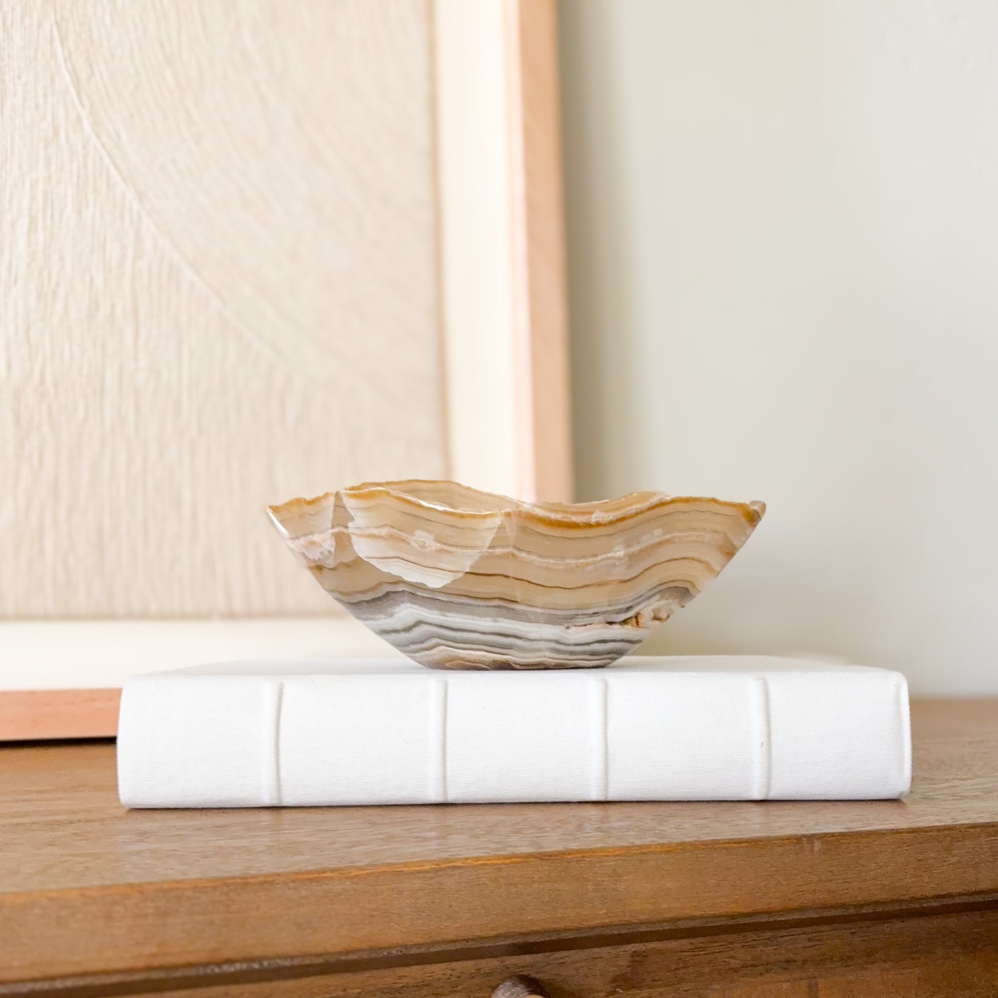 Small hand carved amber onyx bowl with natural banded stone veining in warm honey and cream tones, decorative gemstone dish