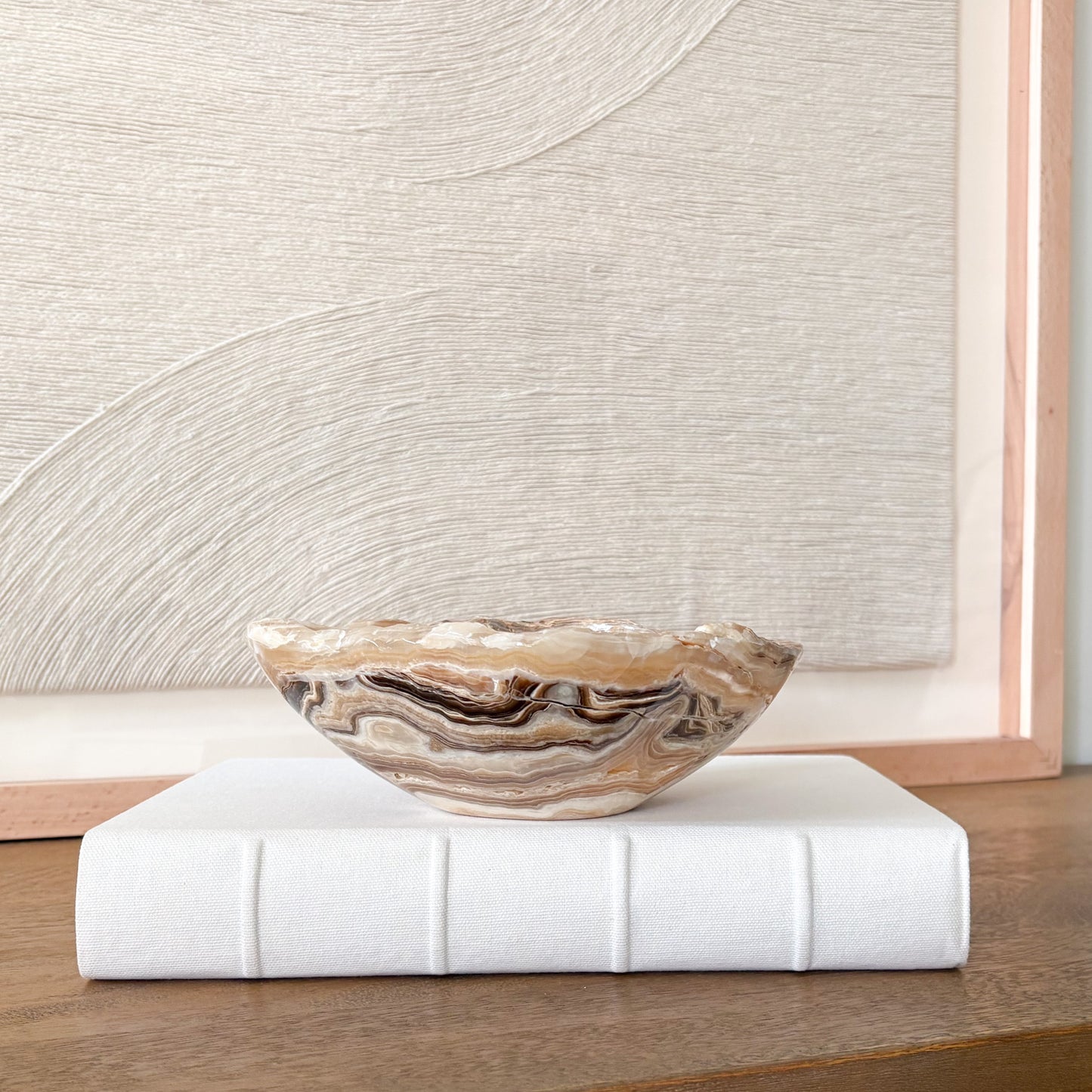 Small amber onyx stone bowl with smooth polished interior and layered cream, honey, and gray veining, handcrafted decorative bowl