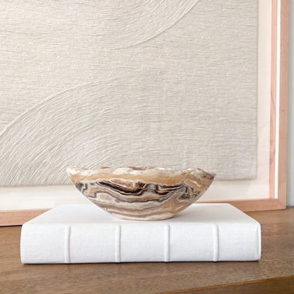 Small amber onyx stone bowl with smooth polished interior and layered cream, honey, and gray veining, handcrafted decorative bowl