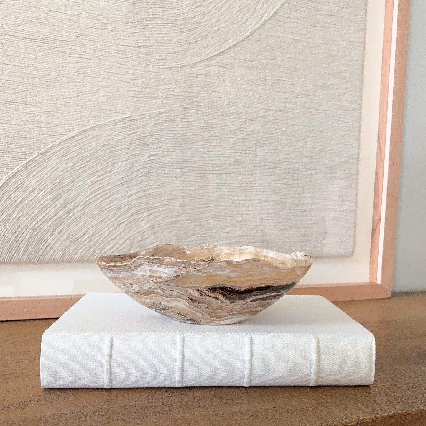 Small hand carved amber onyx bowl with natural banded stone veining in warm honey and cream tones, decorative gemstone dish