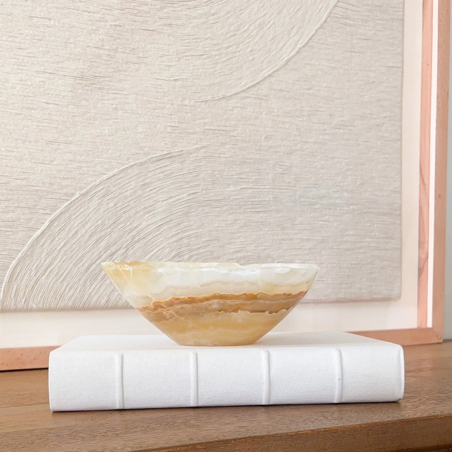 Small hand carved amber onyx bowl with natural banded stone veining in warm honey and cream tones, decorative gemstone dish