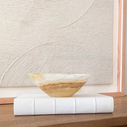 Small hand carved amber onyx bowl with natural banded stone veining in warm honey and cream tones, decorative gemstone dish