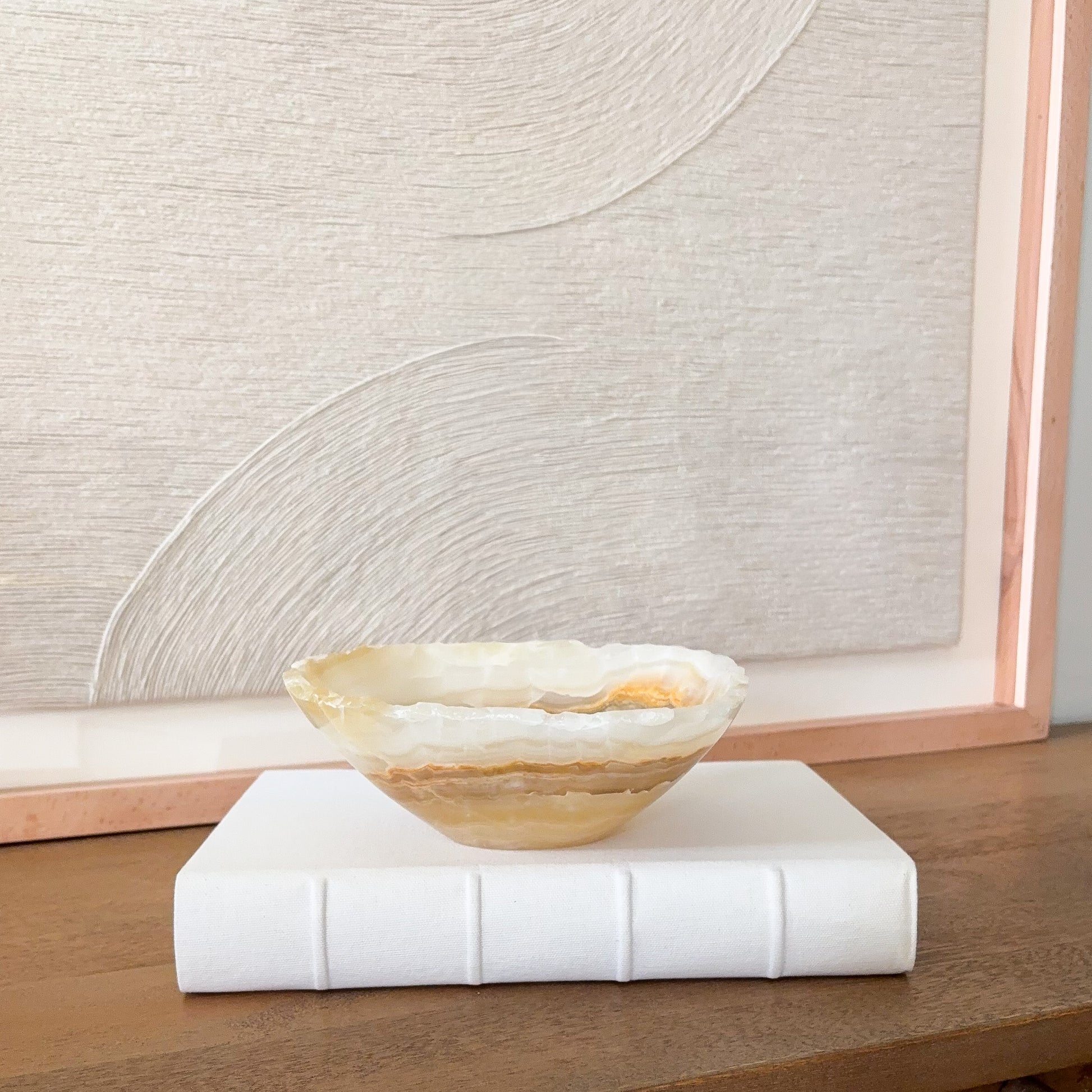 Small hand carved amber onyx bowl featuring warm honey tones and natural veining, elegant stone accent piece