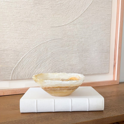 Small hand carved amber onyx bowl featuring warm honey tones and natural veining, elegant stone accent piece