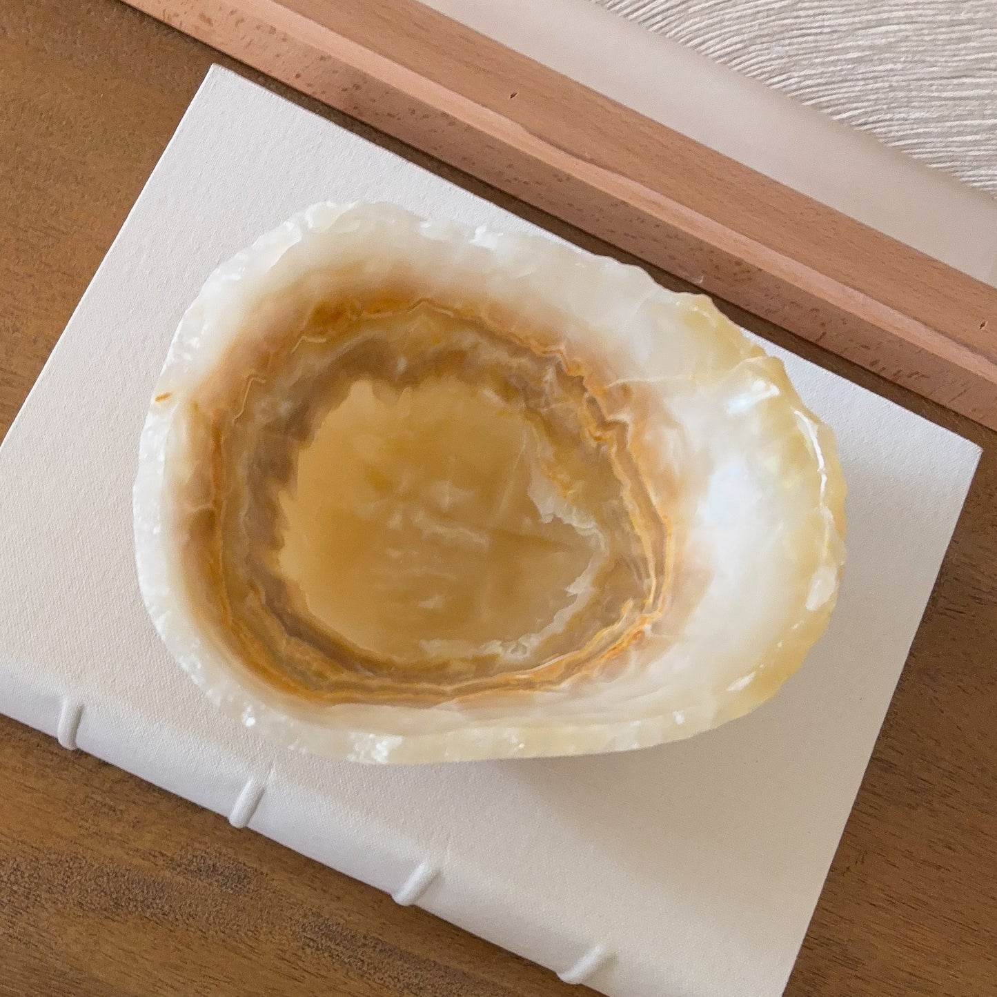 Small hand carved amber onyx bowl with smooth polished finish and rich golden brown veining, decorative stone bowl