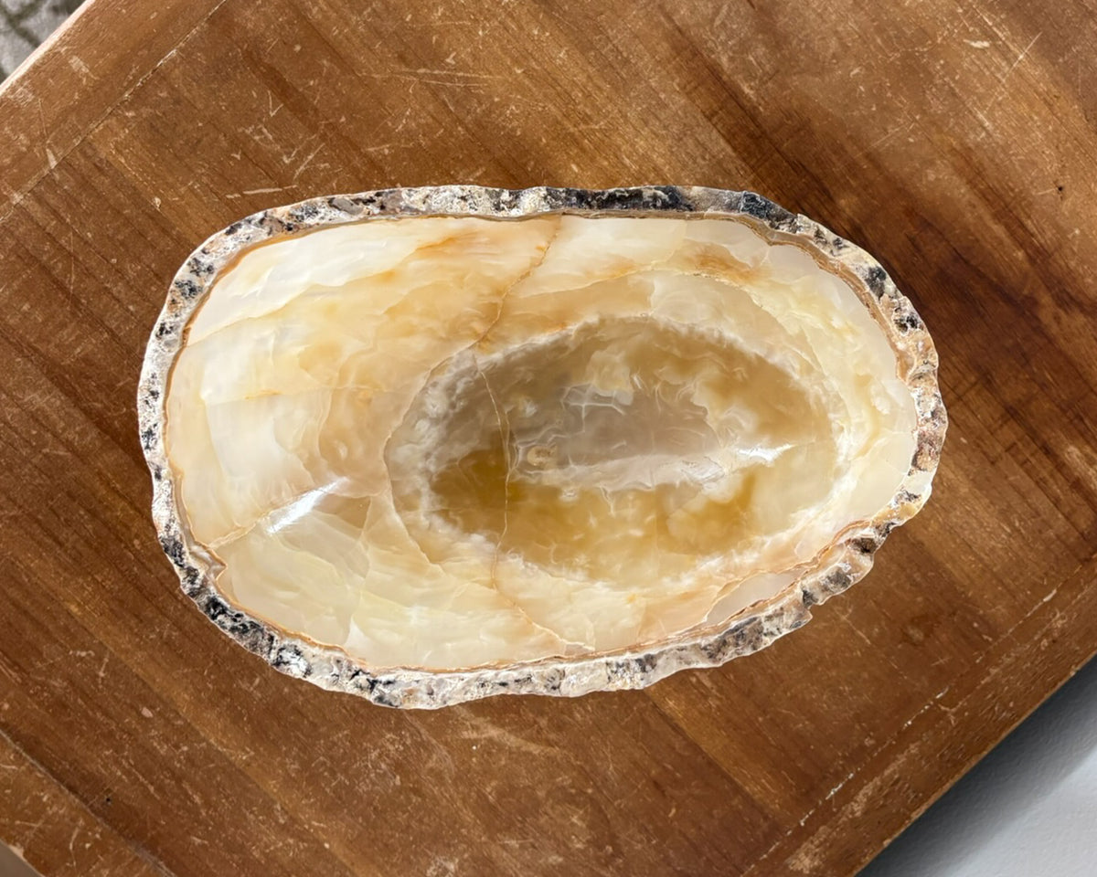 Small decorative amber onyx bowl featuring sculptural form and polished interior