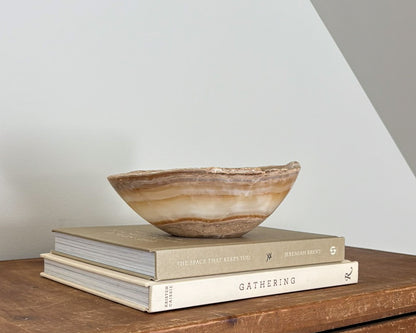 Small amber onyx decorative bowl featuring rich caramel tones and translucent stone