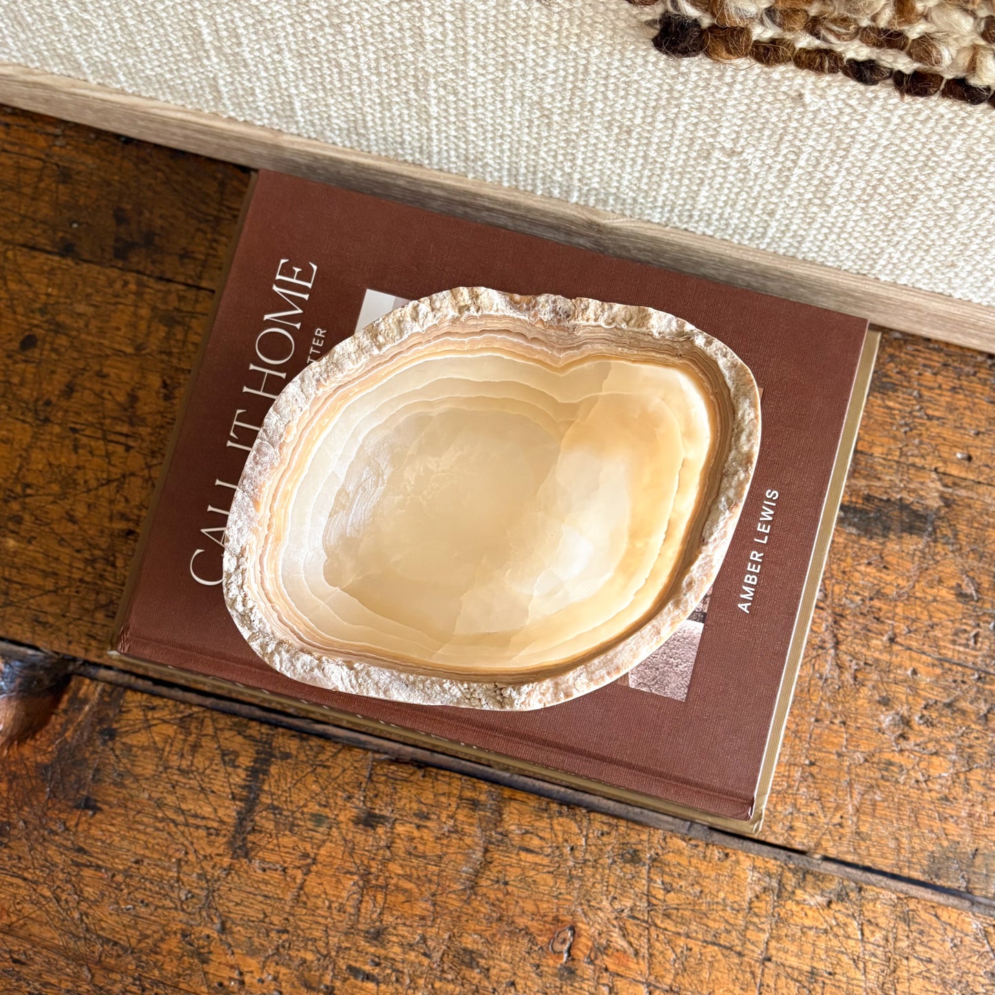 Natural amber onyx bowl hand carved from stone, minimalist decorative accent on wooden surface