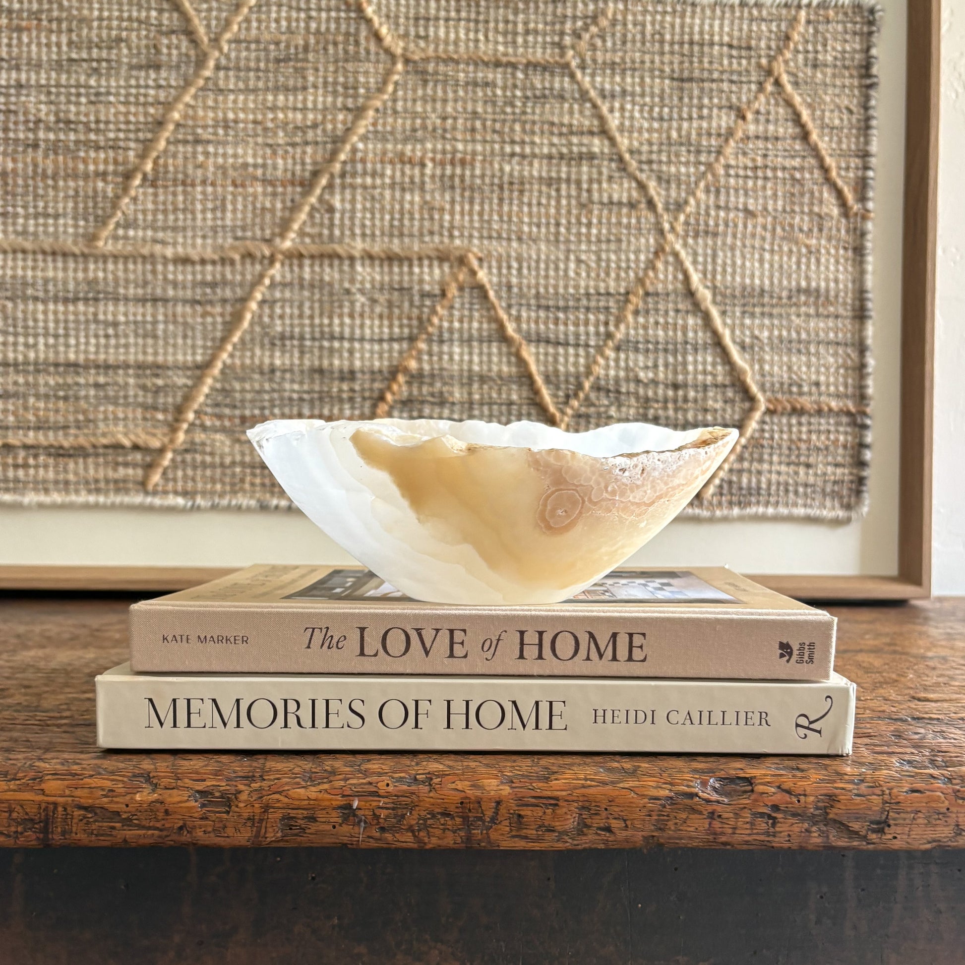 Decorative onyx bowl on top of two books with a textured wall in the background