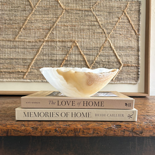 Decorative onyx bowl on top of two books with a textured wall in the background