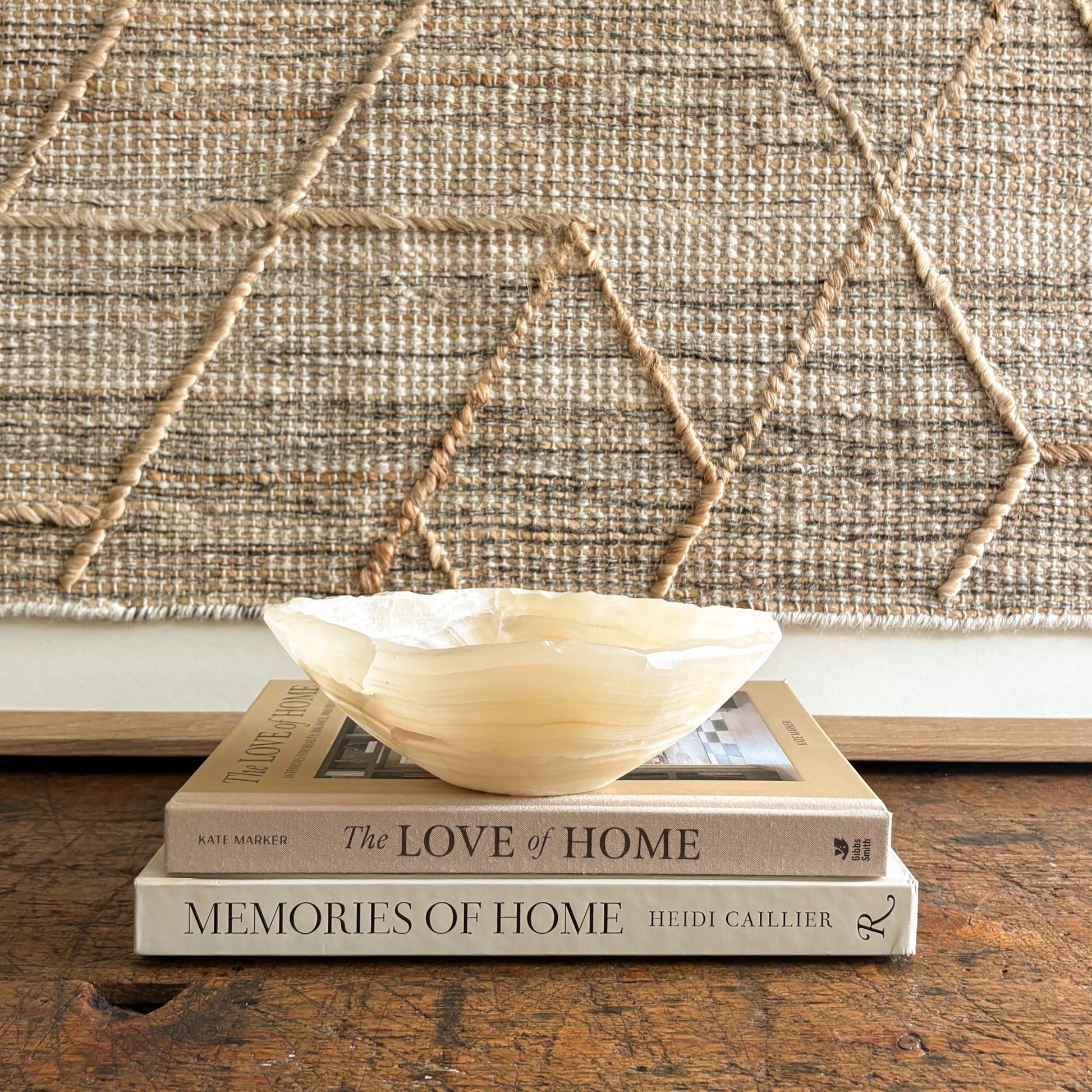 Decorative onyx bowl on top of two books with a textured wall in the background