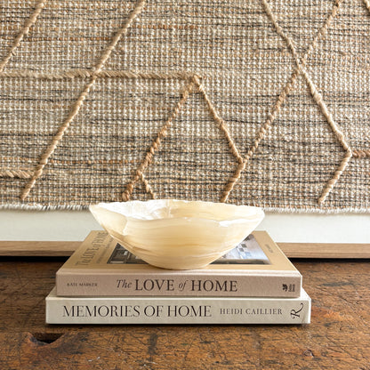 Decorative onyx bowl on top of two books with a textured wall in the background
