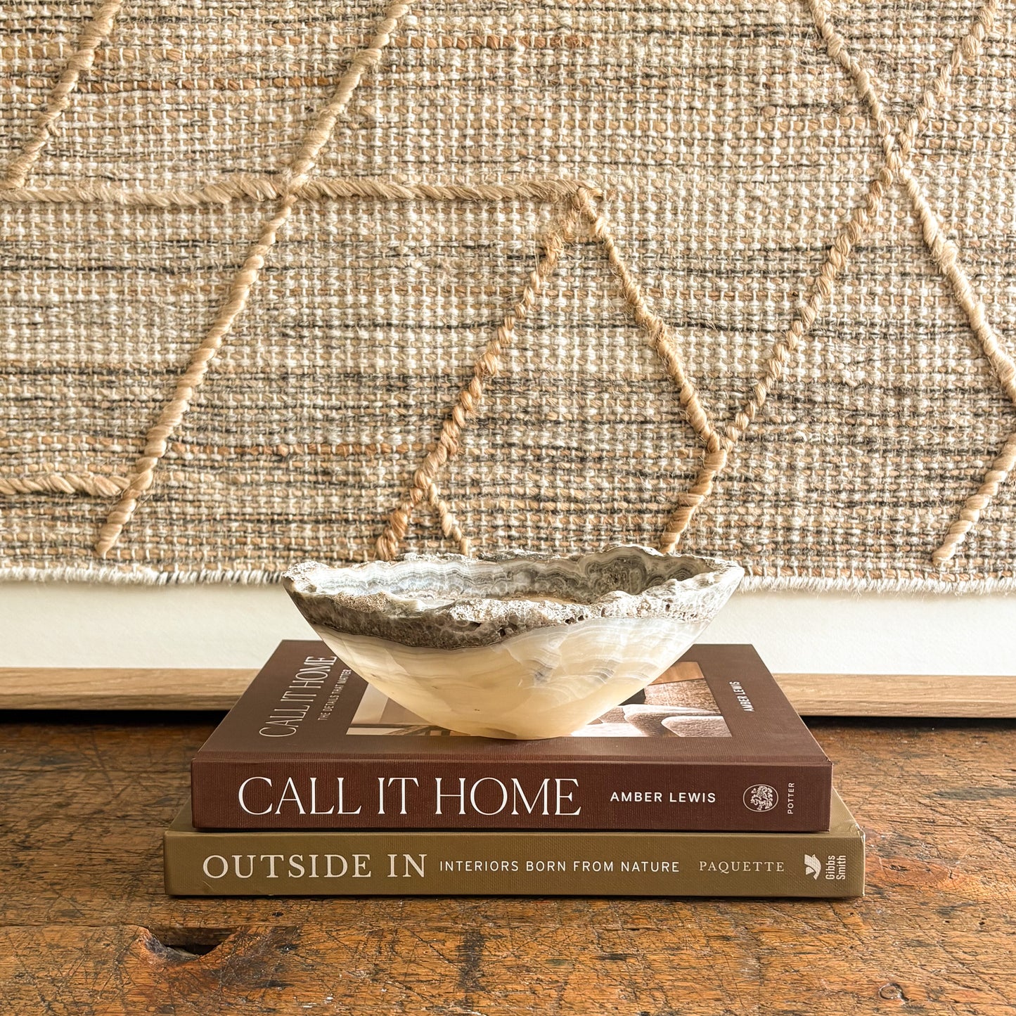 Decorative natural stone bowl on top of two books with a textured wall in the background