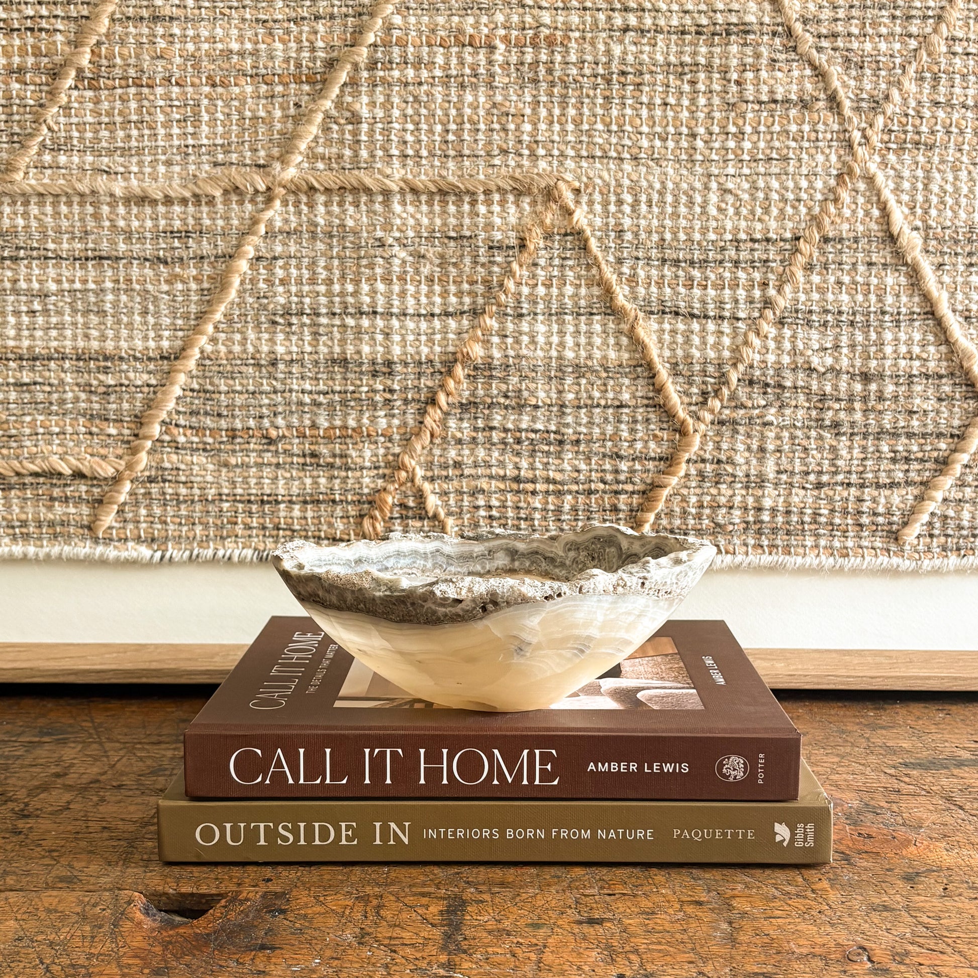 Decorative natural stone bowl on top of two books with a textured wall in the background